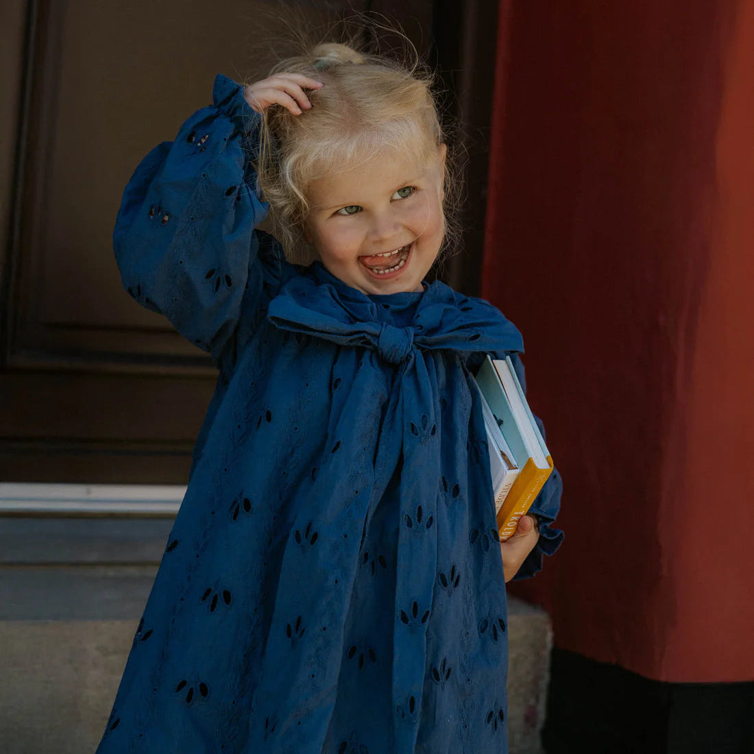 Child in a blue dress standing in front of a door