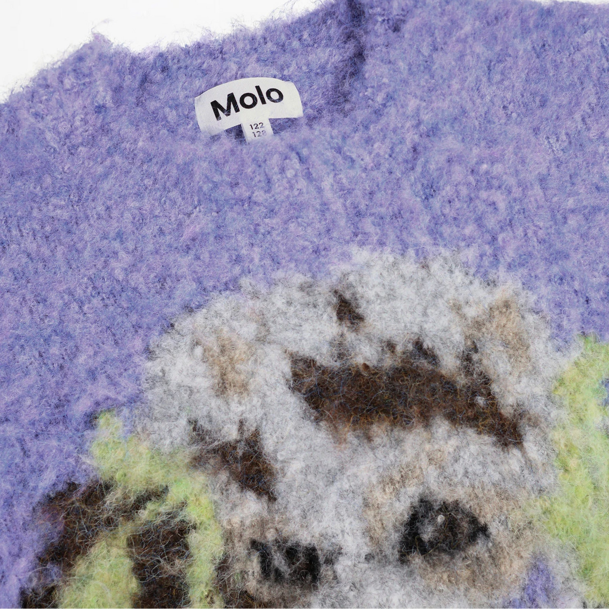 Close-up of a fuzzy knit sweater in lavender purple with a white collar label reading Molo, plus part of a multicolored animal-face pattern in gray, brown, black, and pale green at the bottom.
