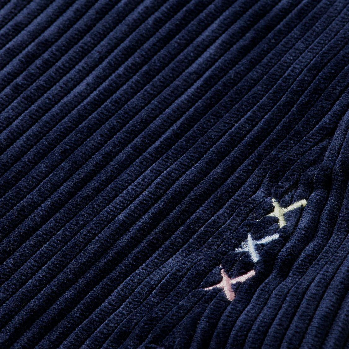 Navy blue fabric with embroidered stars in pink, green, and yellow.