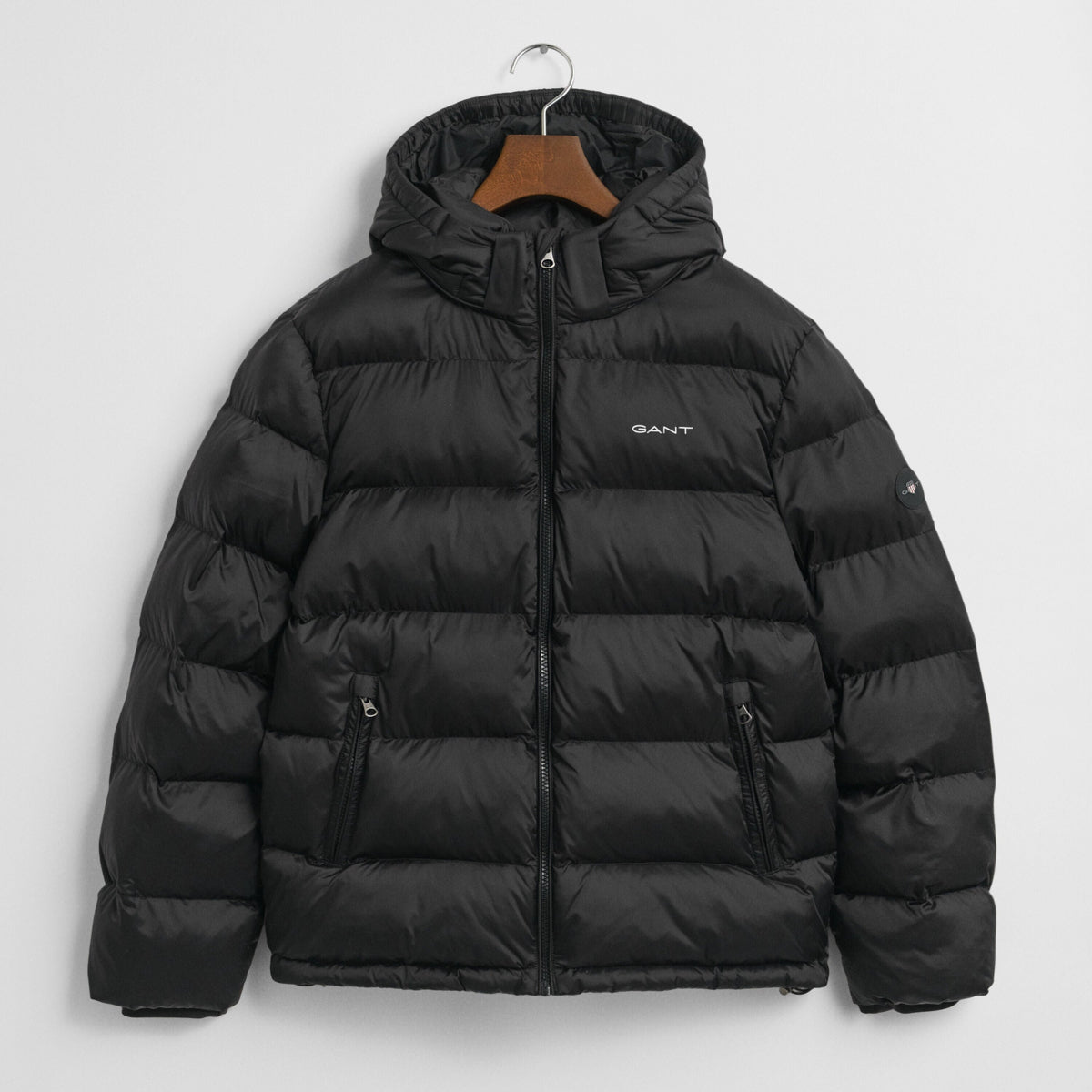 Black GANT puffer jacket on a hanger with a light gray background