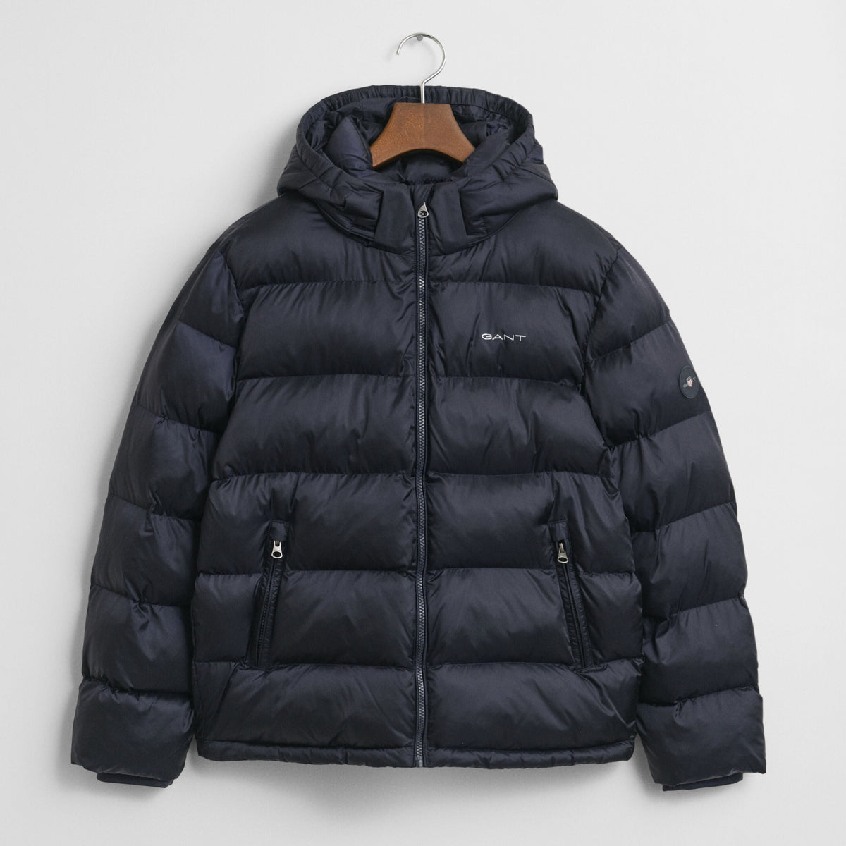 Navy blue puffer jacket on a hanger against a light gray background