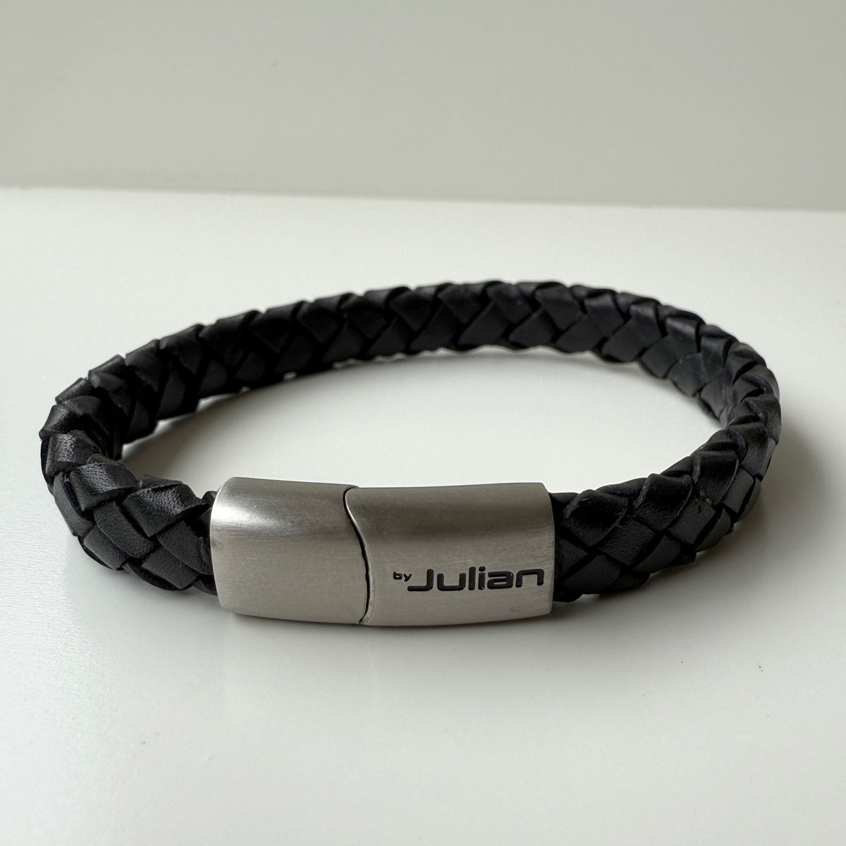 Black braided leather bracelet with silver clasp on a white background