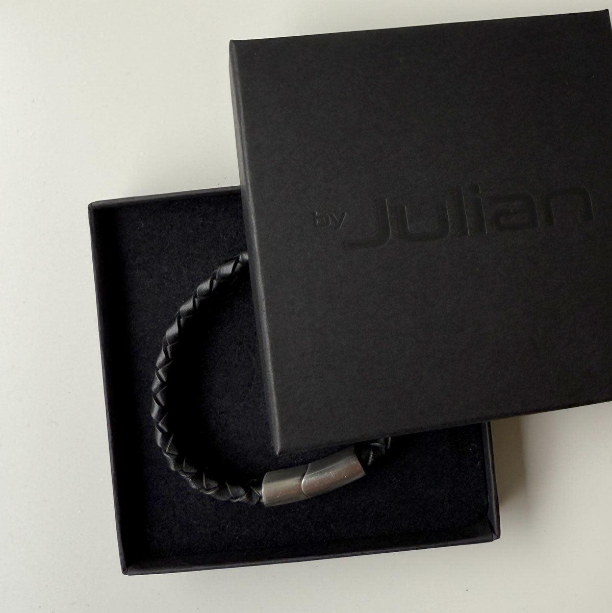 Black braided bracelet in a black box with 'Julian' branding on a white background