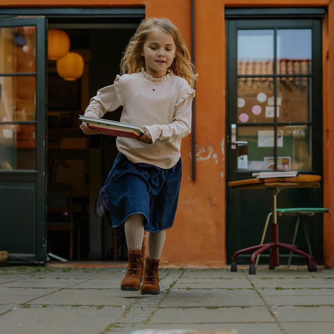 Young girl holding a book in an outdoor setting with a colorful background