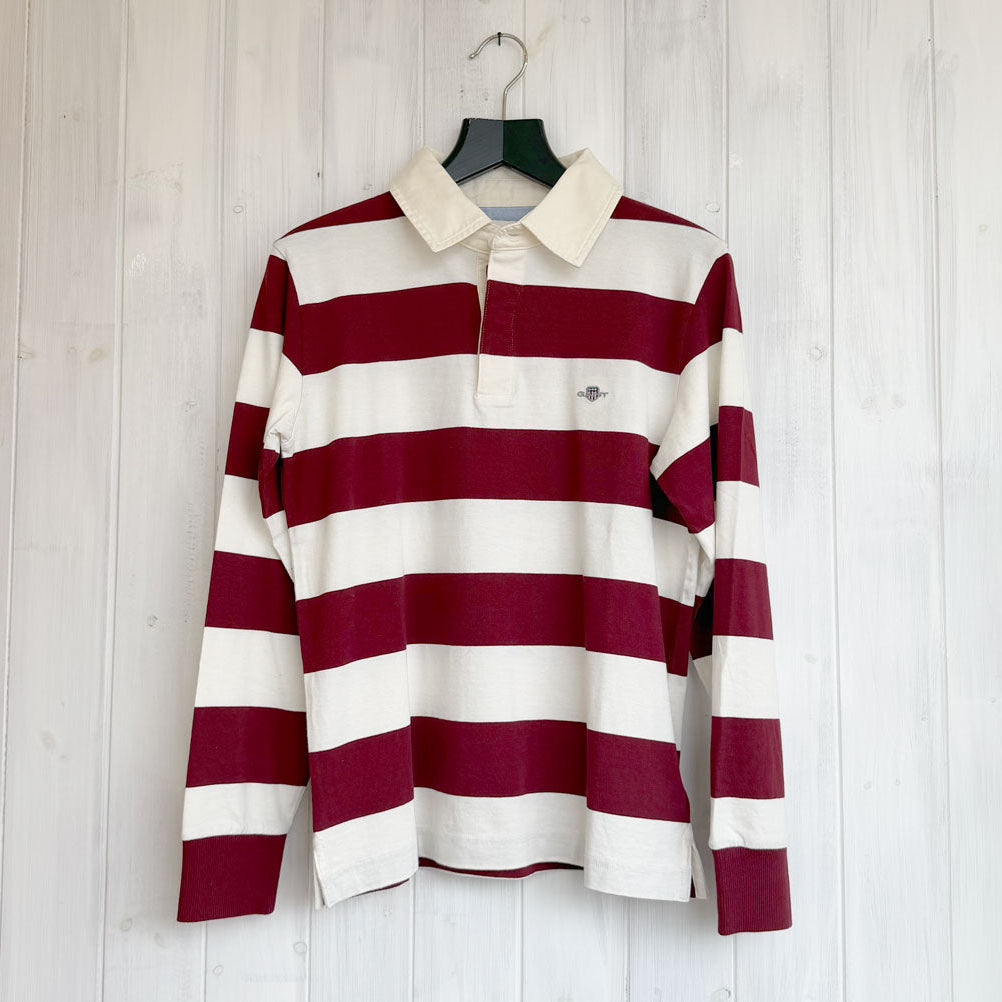 Burgundy and white striped shirt on a hanger against a light wooden panel background