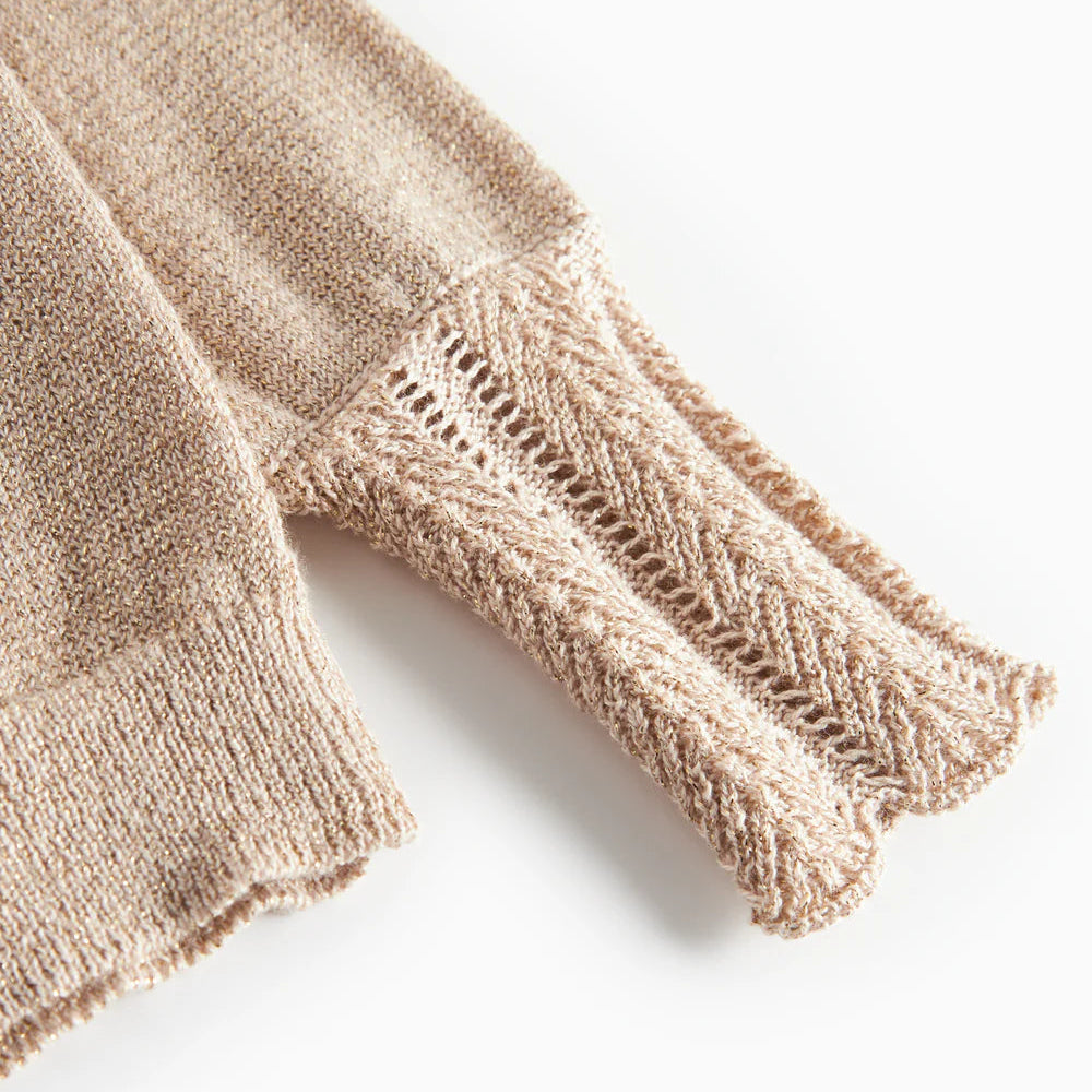 detaljfoto av ärmen av en guldig kofta. fotograferad mot en vit bakgrund. 