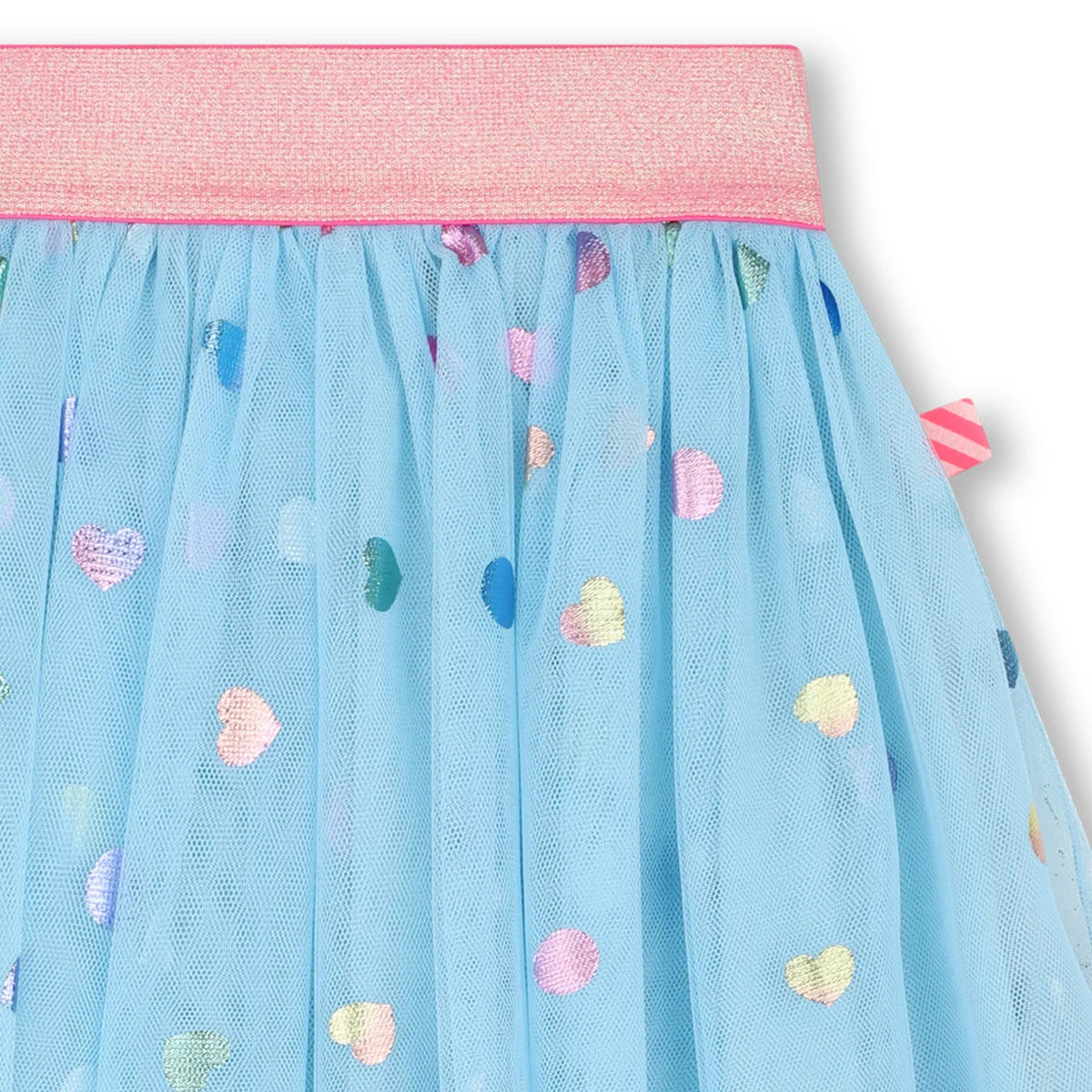 Close-up of a light blue tulle skirt with a pink waistband and scattered pastel heart motifs in pink, yellow, green, and blue.